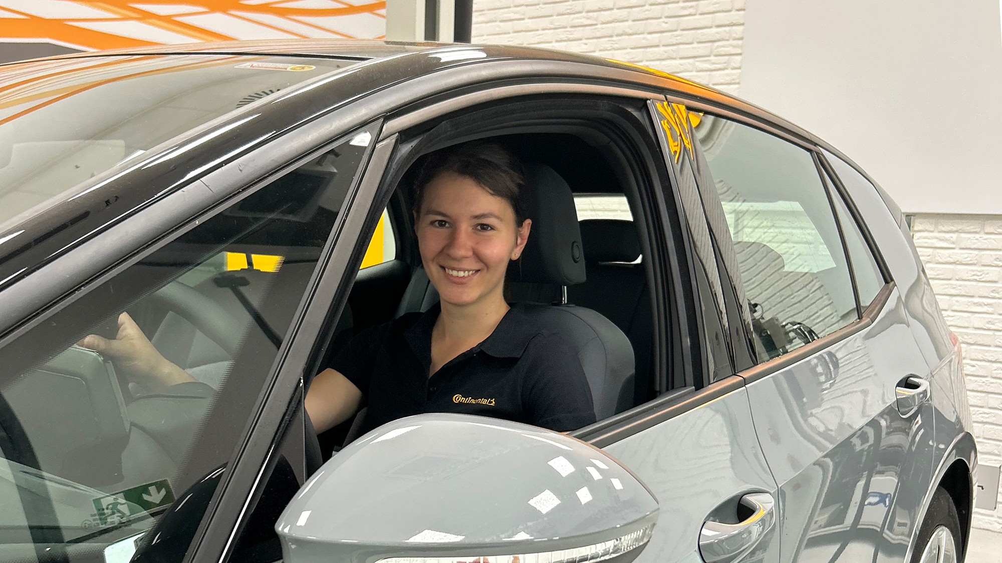 Continental Mitarbeiterin sitzt in grauem Auto mit offenem Fenster.